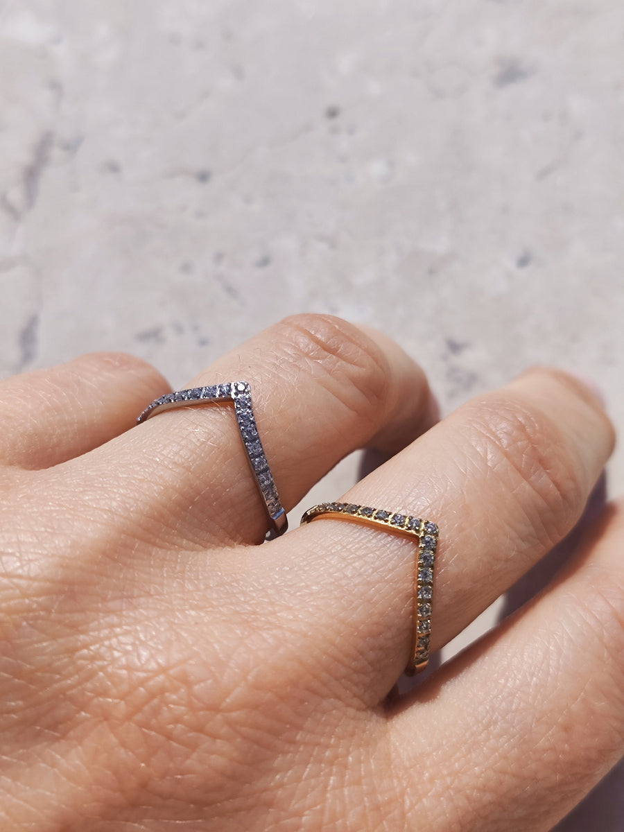 Coppia di anelli Ilaria in acciaio inossidabile e strass indossati da una mano femminile su uno sfondo color marmo. Si evidenzia il design a punta dell'anello e le dimensioni rispetto alla mano.