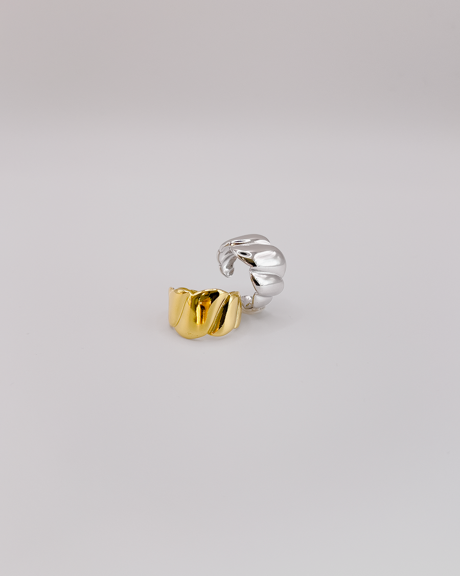 Coppia di anelli Michelle in acciaio inossidabile color oro e argento. Hanno una lavorazione trasversale che ricorda i croissant. L'anello oro è rappresentato frontalmente e quello argento è ripreso in tre quarti.