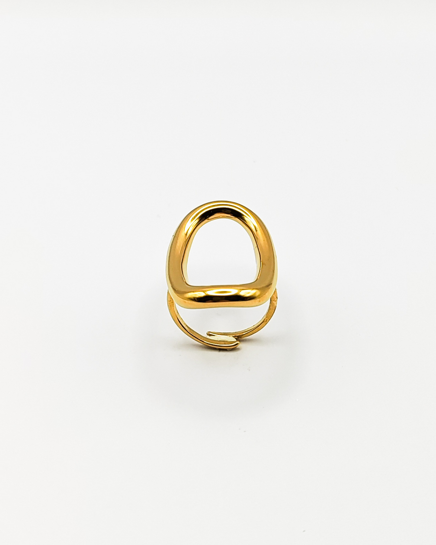 Anello Altea in acciaio inossidabile color oro. È fotografato rivolto verso l'alto e si notano sia l'ovale traforato che si trova sulla parte superiore, sia la chiusura regolabile sul retro.