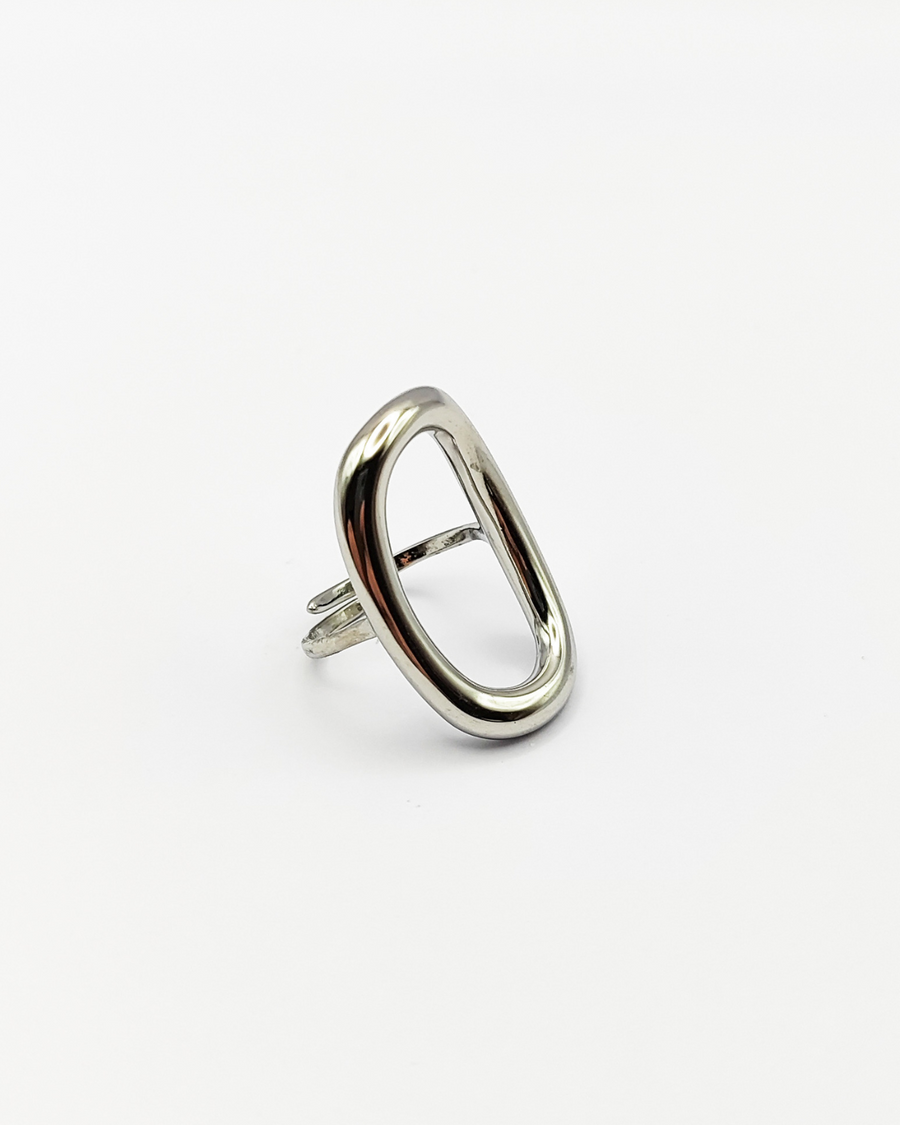 Anello Altea in acciaio inossidabile color argento. È fotografato leggermente di lato, rivolto verso destra. Si notano sia l'ovale traforato sulla parte superiore, che la chiusura regolabile su quella inferiore.