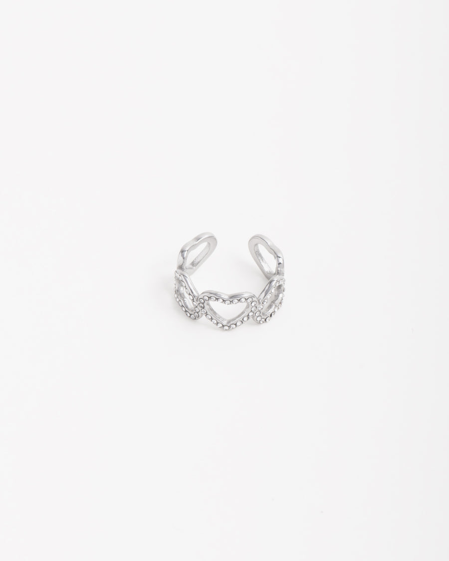 Anello Angelica in acciaio inossidabile color oro . Ha un design a fascia formato da 5 cuori: i tre centrali  hanno una fila di strass mentre i due finali sono lisci. Il verso dei cuori è alternato ed è regolabile sul retro.