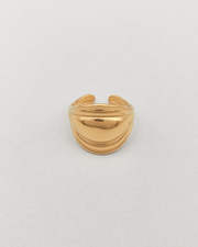 Anello Carlotta in acciaio inossidabile anallergico color oro. È rappresentato frontalmente su uno sfondo grigio chiaro. Ha una forma bombata al centro che si ristringe verso i lati ed ha un finish lucido.