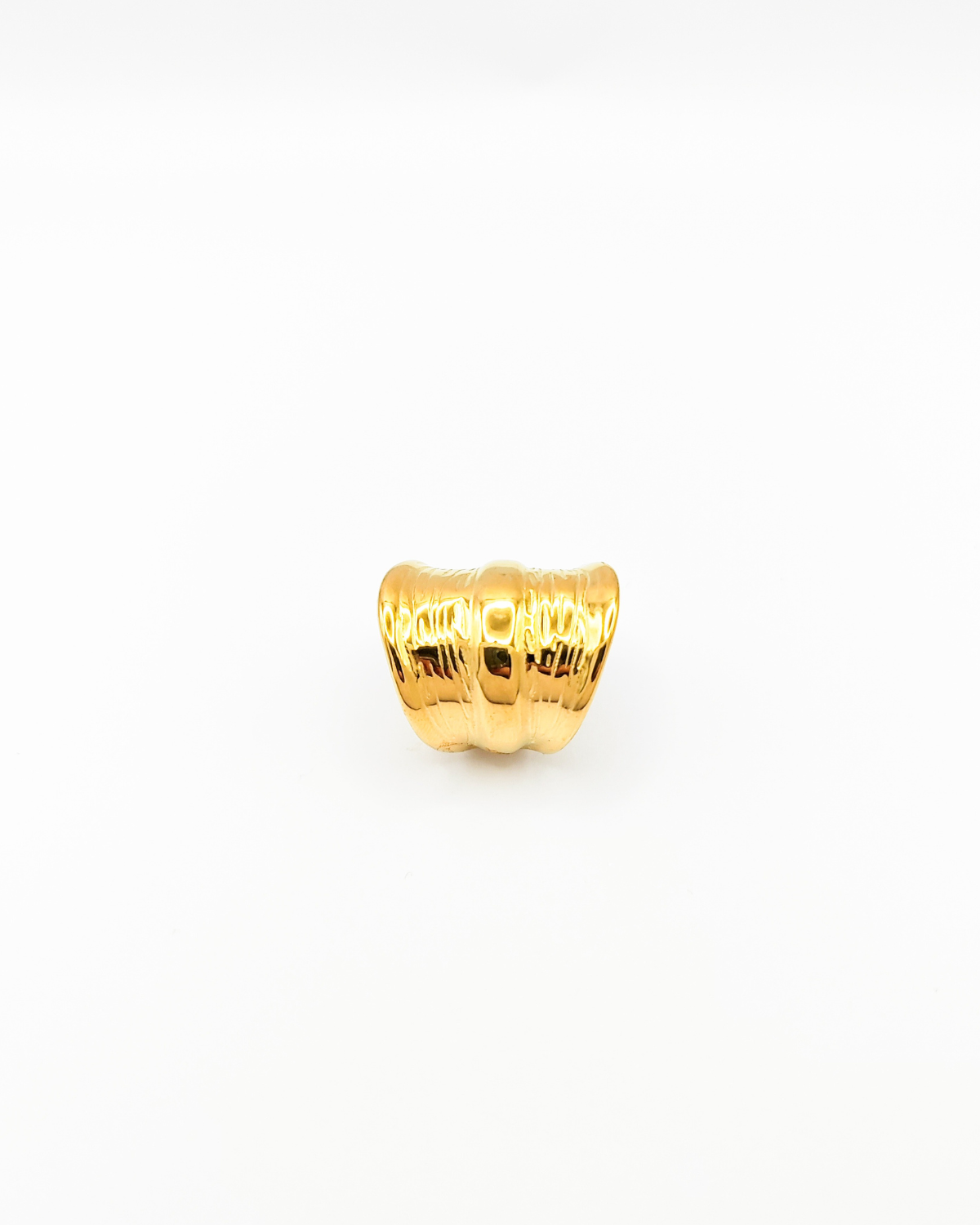 Anello Odine in acciaio inossidabile color oro. È fotografato rivolto verso l'alto e lascia vedere bene la forma più larga al centro che si restringe verso il retro. Ha una fascia più sporgente al centro mentre verso le estremità il design è drappeggiato.