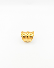 Anello Odine in acciaio inossidabile color oro. È fotografato rivolto verso l'alto e lascia vedere bene la forma più larga al centro che si restringe verso il retro. Ha una fascia più sporgente al centro mentre verso le estremità il design è drappeggiato.