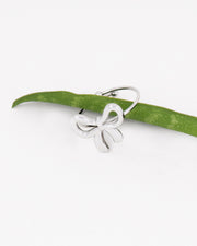 Anello Pamela, regolabile in acciaio inossidabile decorato da un fiocco anch'esso in acciaio, colorazione argento. È infilato in una foglia verde che lo sorregge. L'acciaio è un materiale anallergico e waterproof. È un anello raffinato e delicato.
