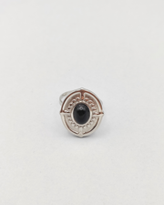 Anello Antonella in acciaio inossidabile anallergico color argento e pietra onice. È di forma ovale e rappresentato frontalmente. Si vede la pietra onice al centro, contornata da una lavorazione a pallini in rilievo, così come il bordo dell'anello e dei trattini che riprendono i quatto punti cardinali.