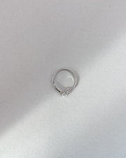Anello Letizia in acciaio inossidabile anallergico in colore argento e zirconi. La pietra centrale è accompagnata da piccole pietre sui lati. E' rappresentato dall'alto su uno sfondo grigio.