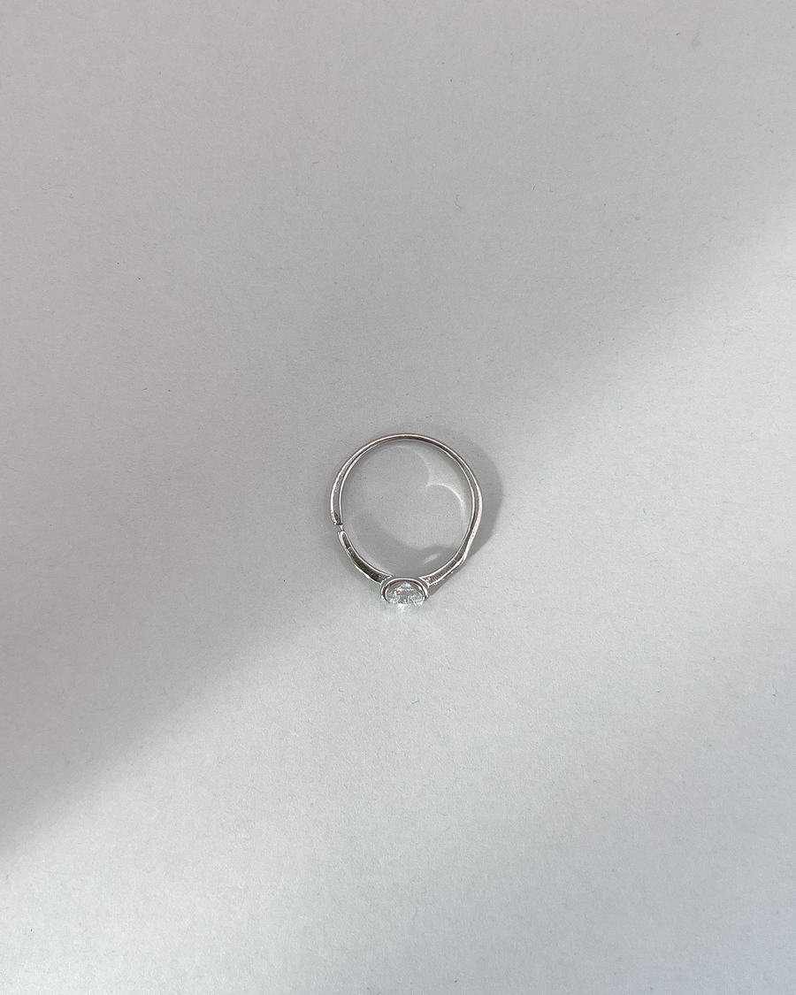 Anello Letizia in acciaio inossidabile anallergico in colore argento e zirconi. La pietra centrale è accompagnata da piccole pietre sui lati. E' rappresentato dall'alto su uno sfondo grigio.