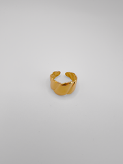 Anello Michelle in acciaio inossidabile color oro. Ha una lavorazione trasversale che ricorda i croissant. E' ripreso frontalmente su sfondo grigio.