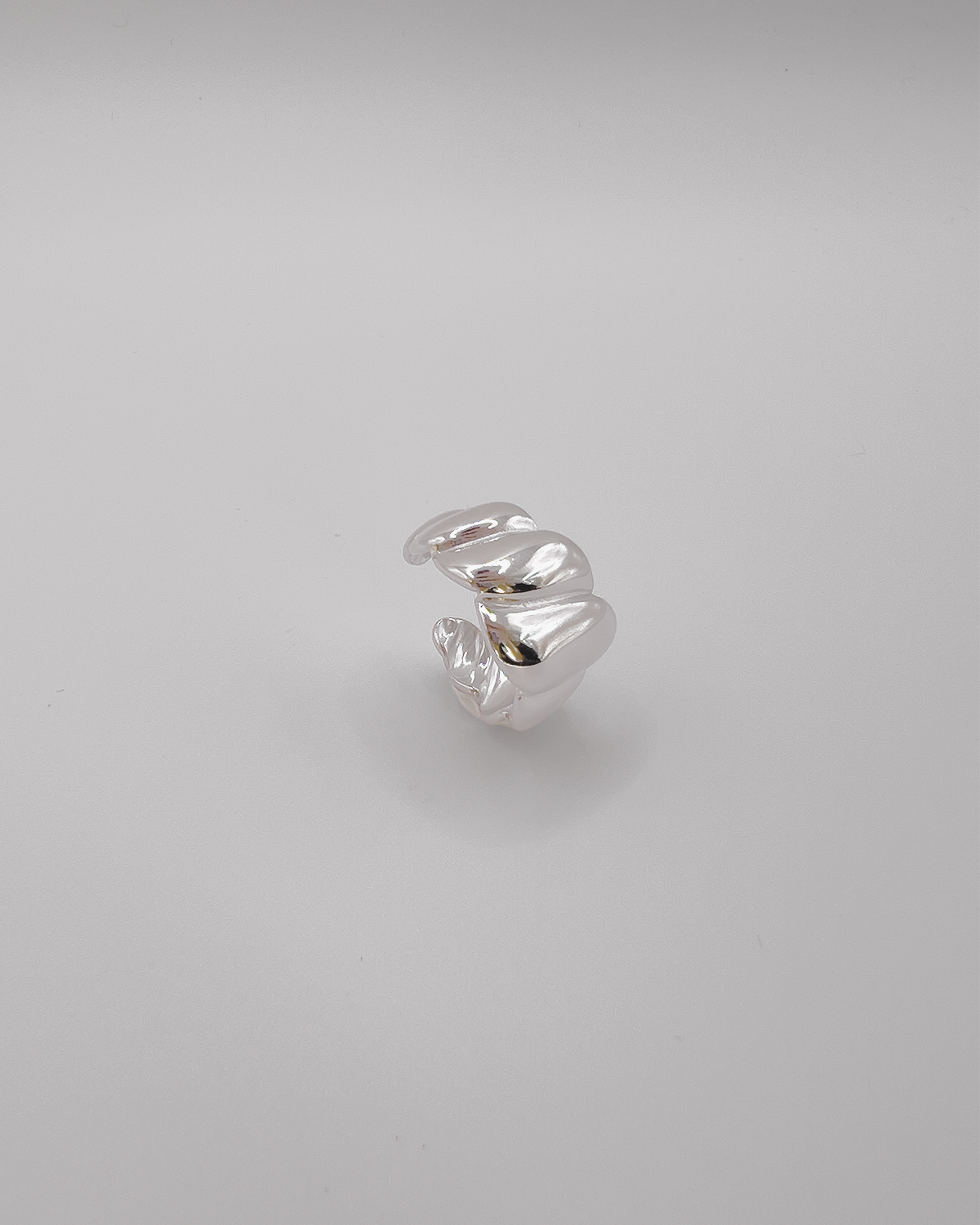 Anello Michelle in acciaio inossidabile color argento. Ha una lavorazione trasversale che ricorda i croissant. E' ripreso in tre quarti da sopra.