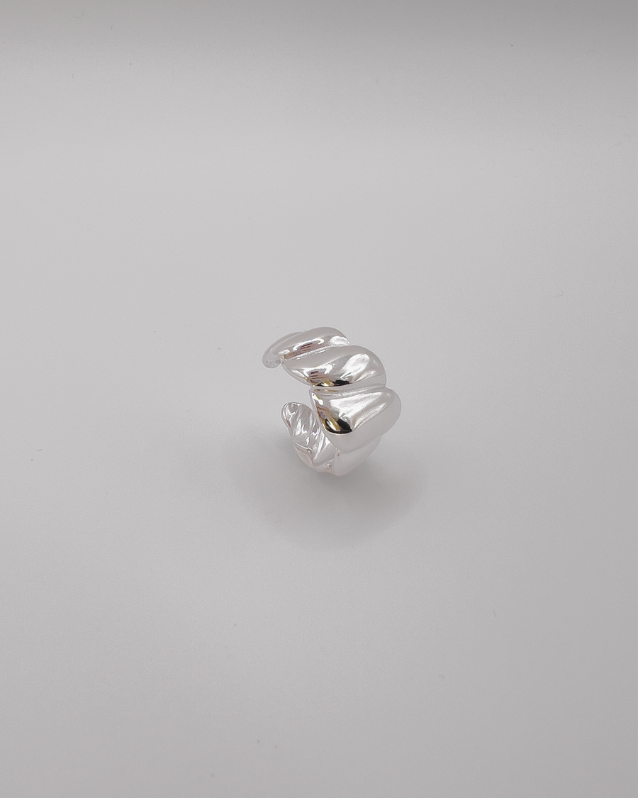 Anello Michelle in acciaio inossidabile color argento. Ha una lavorazione trasversale che ricorda i croissant. E' ripreso in tre quarti da sopra.