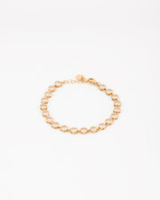 Bracciale Alessia in acciaio inossidabile color oro e strass rotondi con castoni piatti. Fotografato chiuso e in posizione circolare su sfondo bianco. Ha la chiusura a moschettone ed è regolabile oltre ad essere anallergico e waterproof.