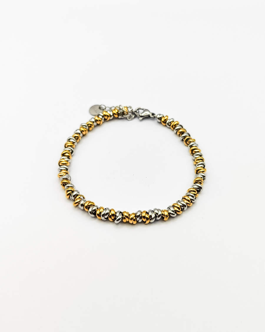 Bracciale Anna in acciaio inossidabile argento e oro. È fotografato dall'alto ed è formato da tanti nodini che si intrecciano tra loro.