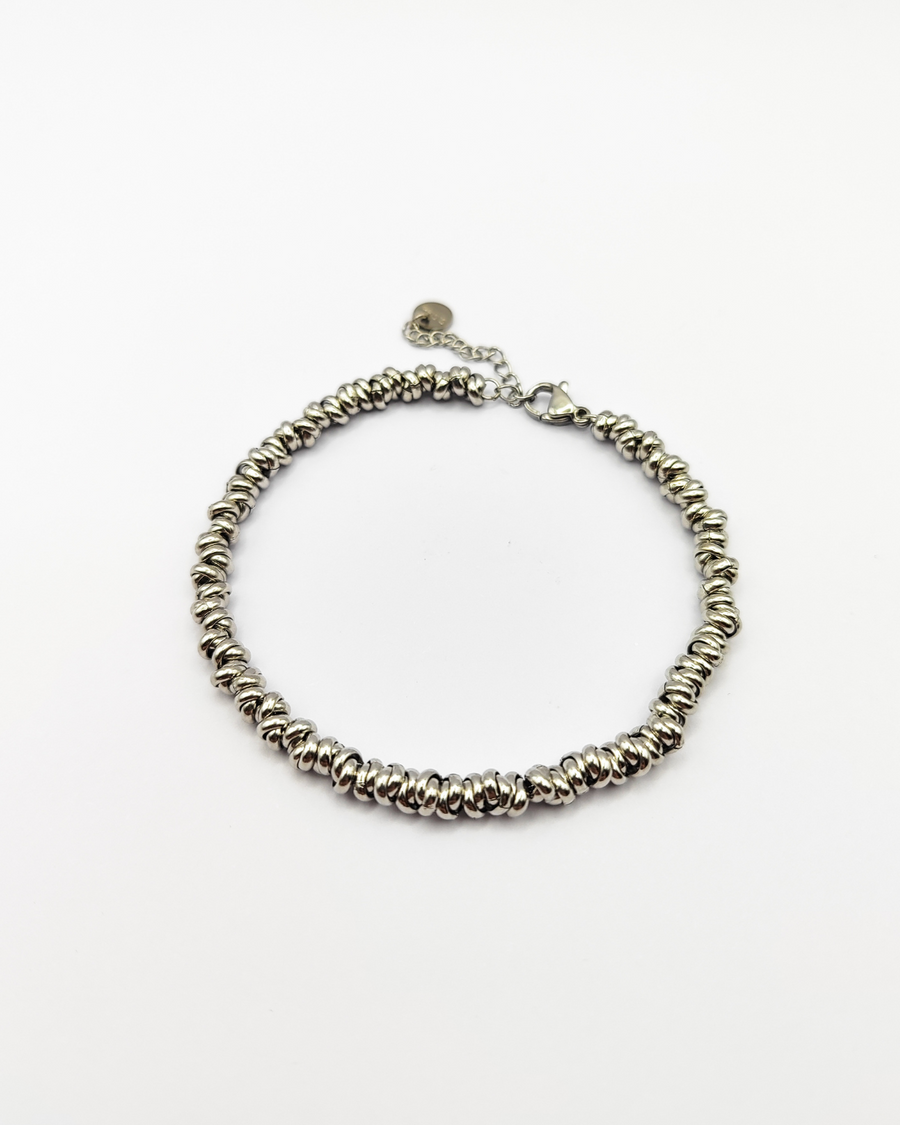 Bracciale Anna in acciaio inossidabile color argento. È fotografato dall'alto ed è formato da tanti nodini che si intrecciano tra loro.