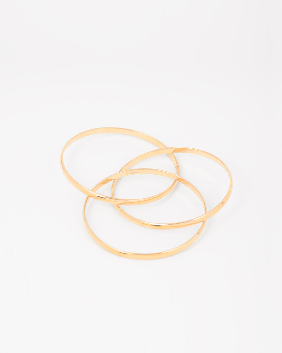Bracciale rigido Paola in acciaio inossidabile color oro, composto da tre bracciali distinti intrecciati tra loro. Qui viene rappresentato aperto per far vedere l'intreccio. Come sempre è in materiale anallergico e waterproof.