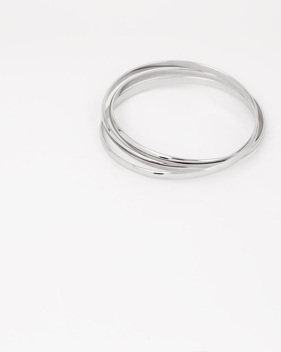 Bracciale rigido Paola in acciaio inossidabile color argento, composto da tre bracciali distinti intrecciati tra loro. Qui viene rappresentato chiuso e si nota l'intreccio. Come sempre è in materiale anallergico e waterproof.