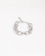 Bracciale Sandra in acciaio inossidabile a maglie larghe ovali color argento, con raccordo centrale a doppia fila di strass. È adagiato chiuso su uno sfondo chiaro. Come sempre è in materiale anallergico e waterproof. La chiusura è a moschettone con catenella per la regolazione.