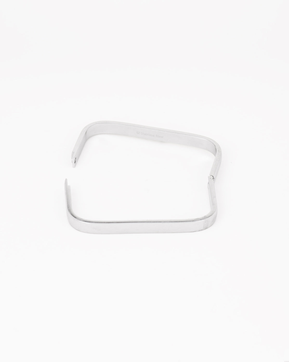 Bracciale rigido Valentina in acciaio inossidabile color argento. È rappresentato aperto e disteso su uno sfondo chiaro. La forma è rettangolare e la chiusura è a scomparsa. È prodotto in materiale resistente all'acqua e anallergico.