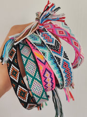 Bracciali in filo intrecciato di vari colori tenuti in mano insieme.