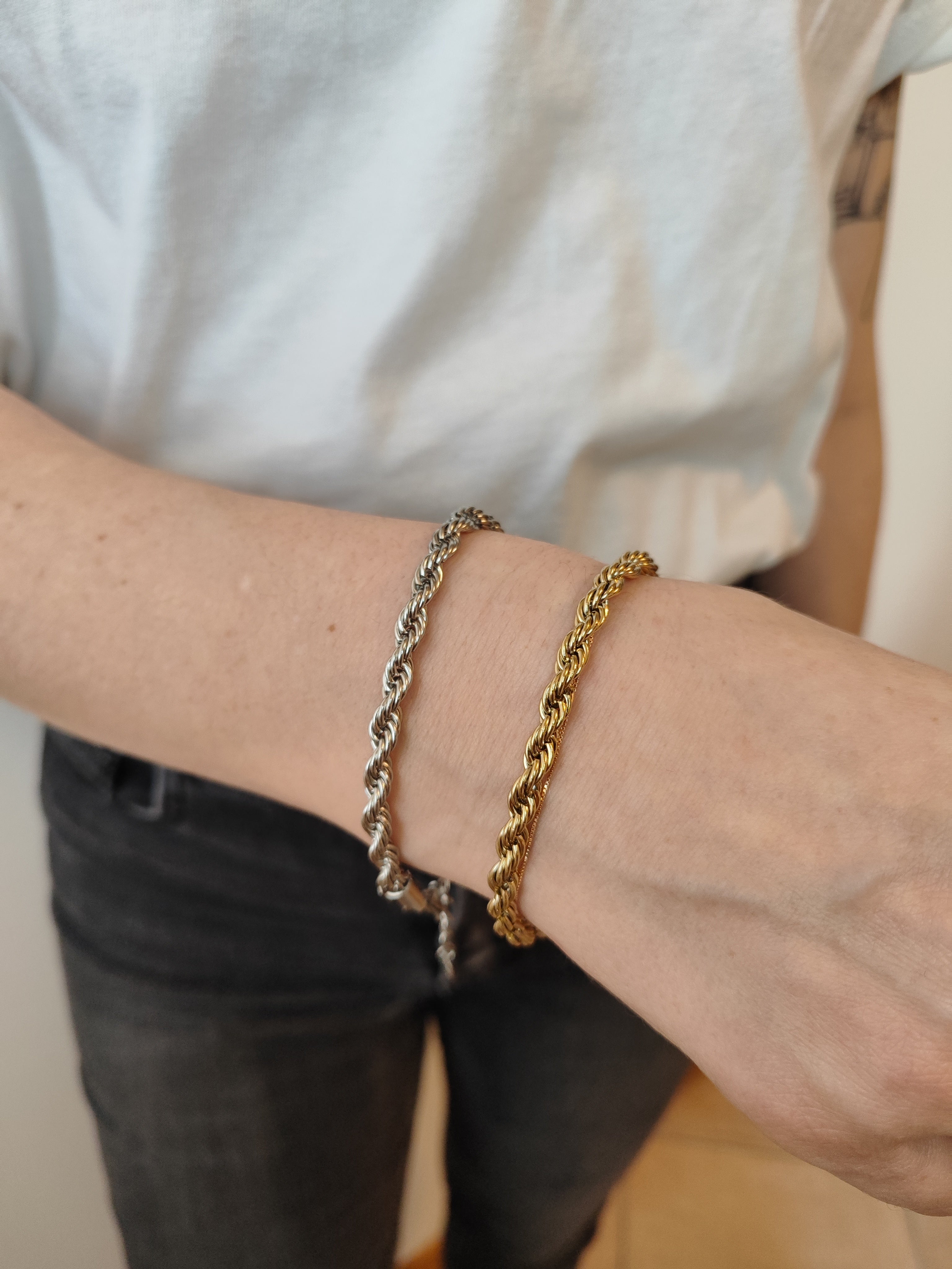 Coppia di bracciali Ester in acciaio inossidabile color oro e argento. Il modello è un torchon e sono indossati da una modella con t-shirt bianca e jeans neri.