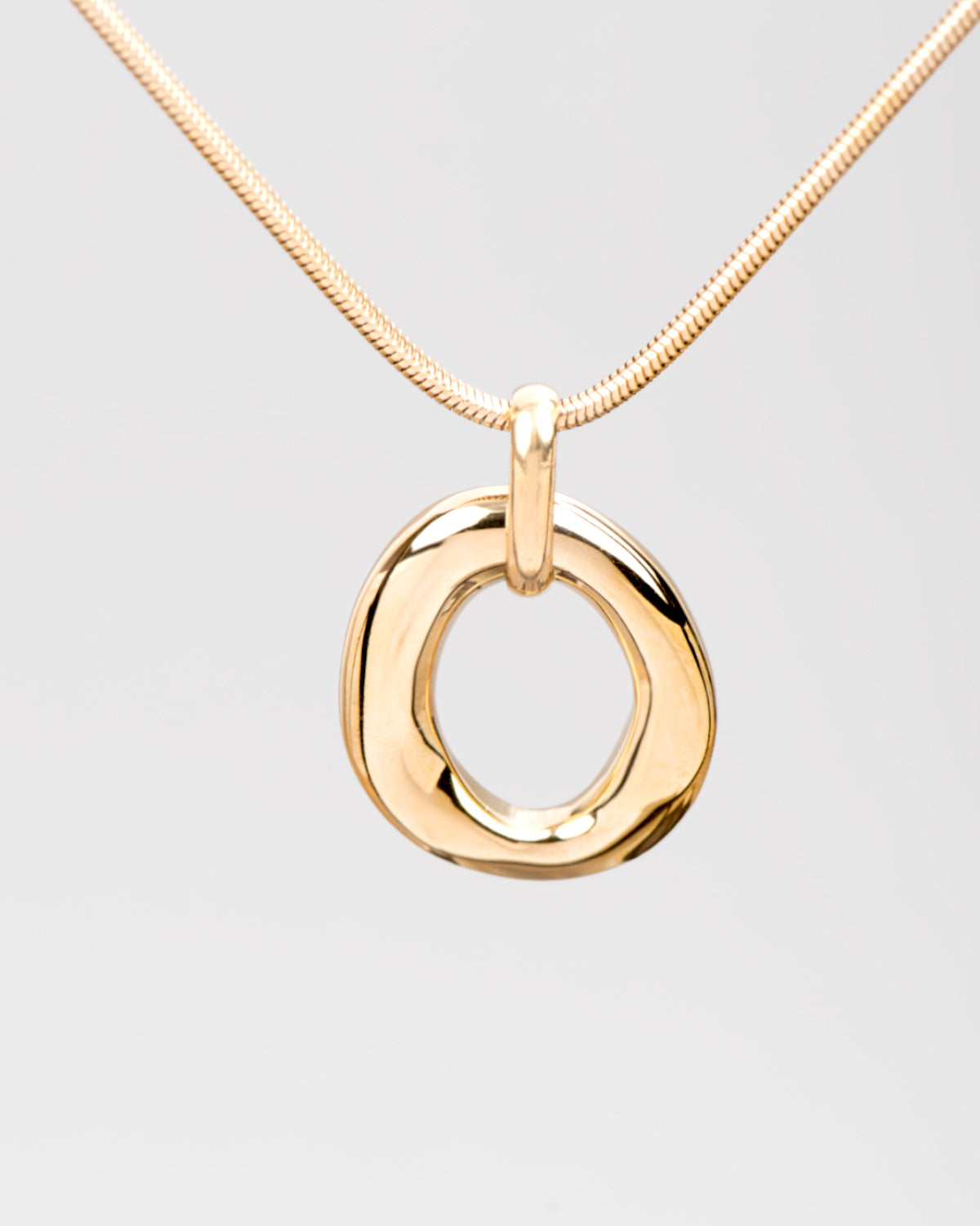 Collana Denise in acciaio inossidabile color oro. Il focus è sul ciondolo ovale di forma irregolare e traforato. Si vede anche la catena in stile coda di topo.