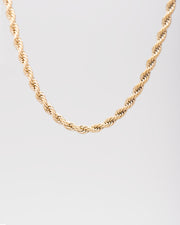 Collana Ester in acciaio inossidabile color oro, modello torchon. È raffigurata appesa su sfondo chiaro. Si notano bene le maglie intrecciate.