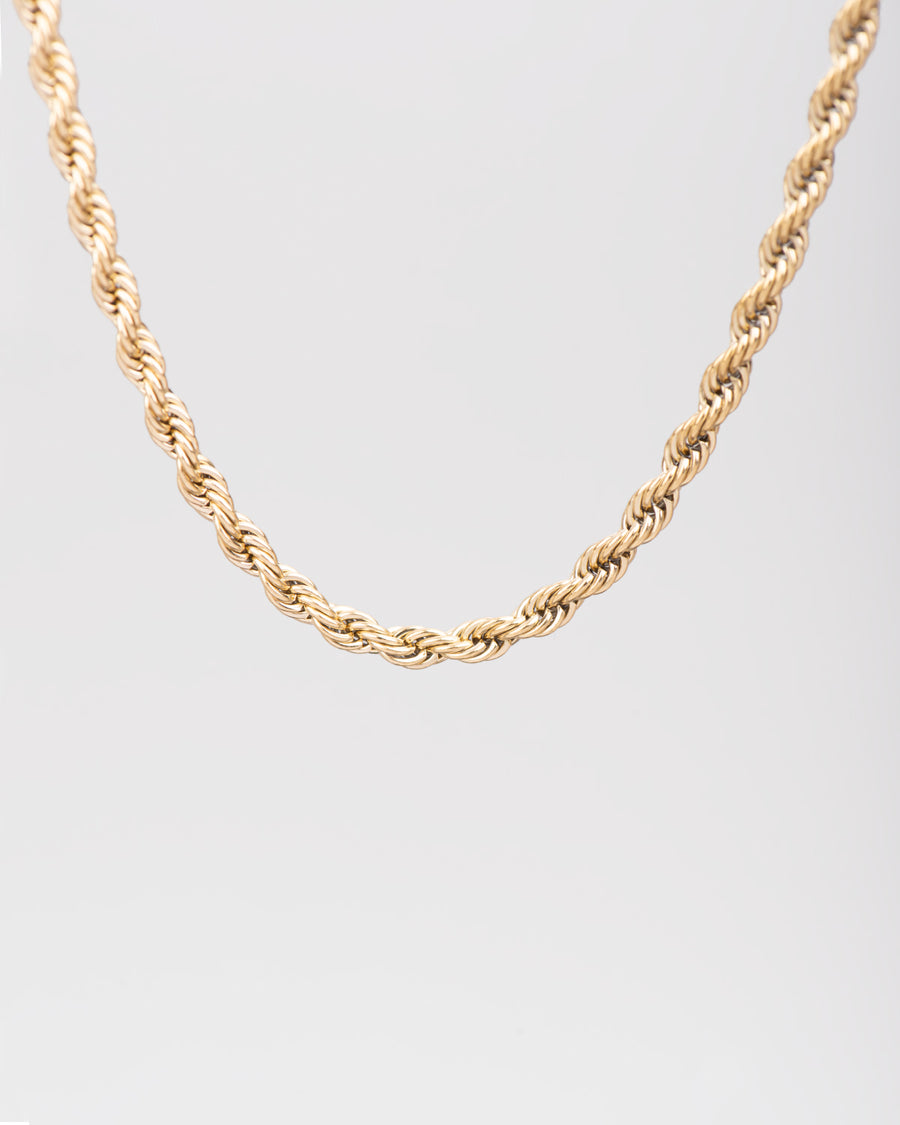 Collana Ester in acciaio inossidabile color oro, modello torchon. È raffigurata appesa su sfondo chiaro. Si notano bene le maglie intrecciate.