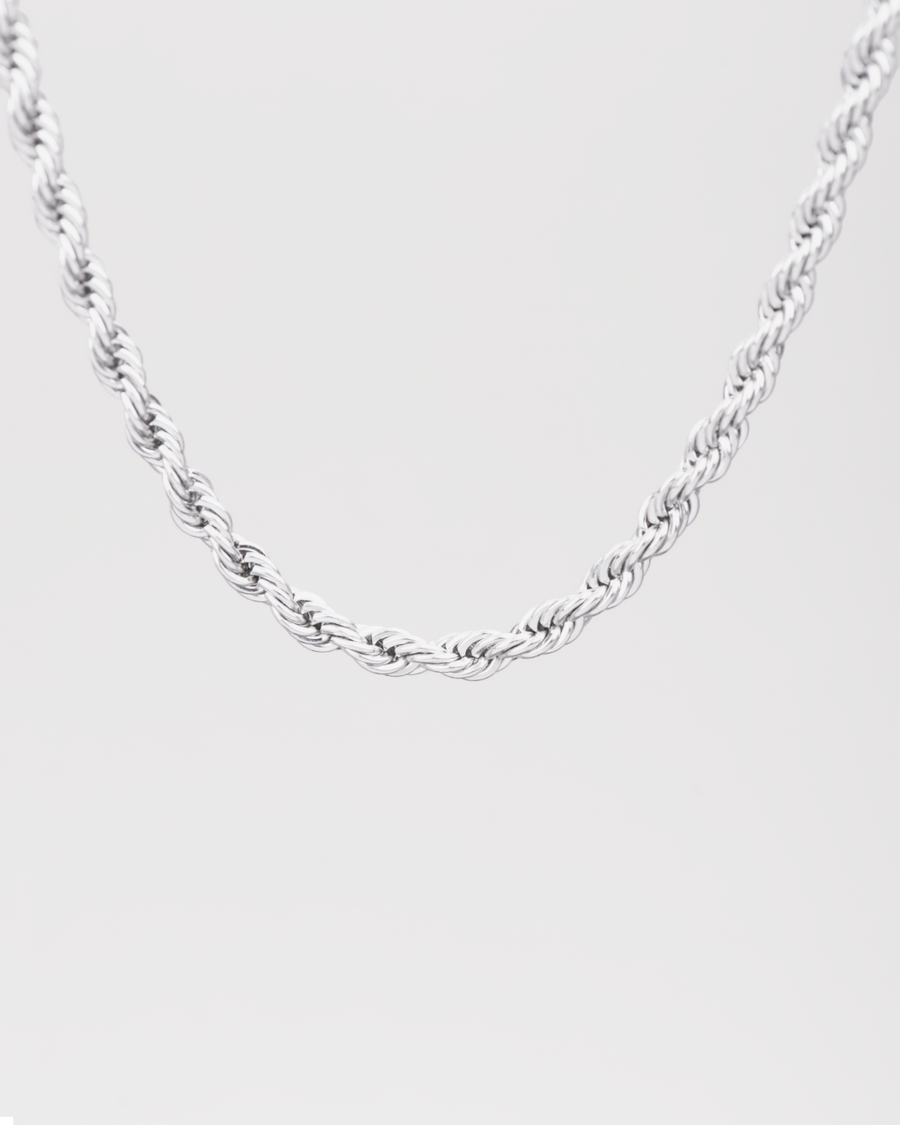 Collana Ester in acciaio inossidabile color argento, modello torchon. È raffigurata appesa su sfondo chiaro. Si notano bene le maglie intrecciate.