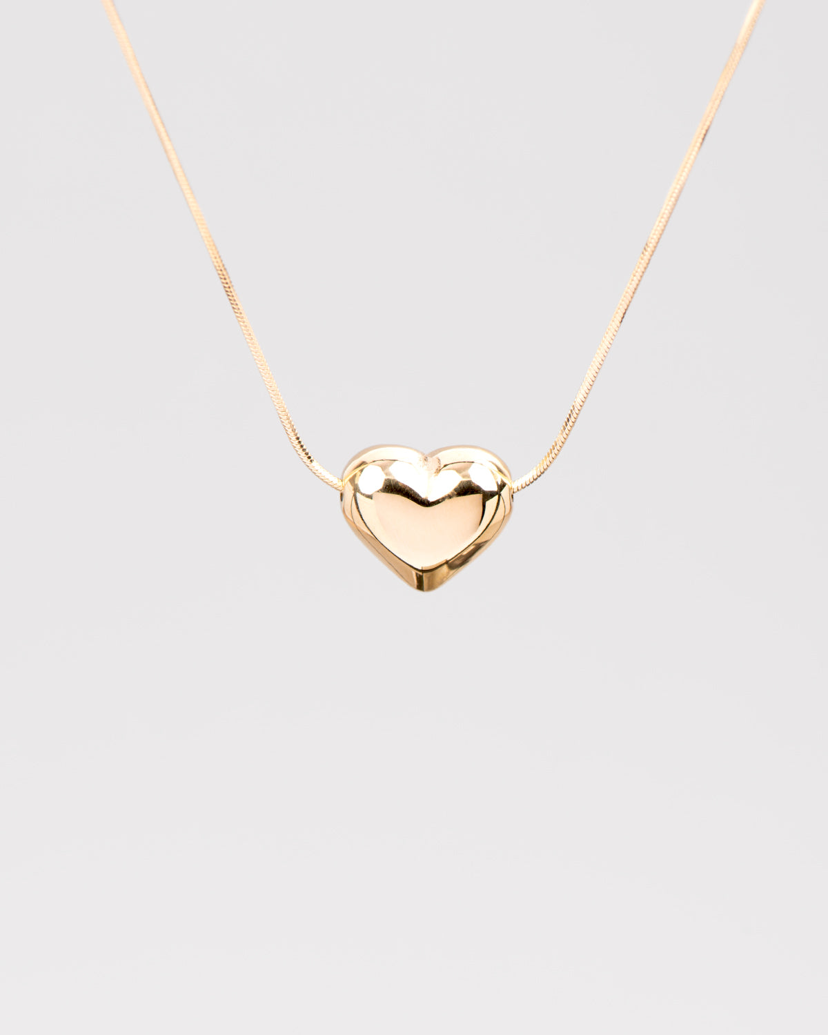 Dettaglio sul cuore bombato in acciaio inossidabile della collana Jessica nella versione oro. Il finish è molto lucido e la catenina molto sottile e fine.