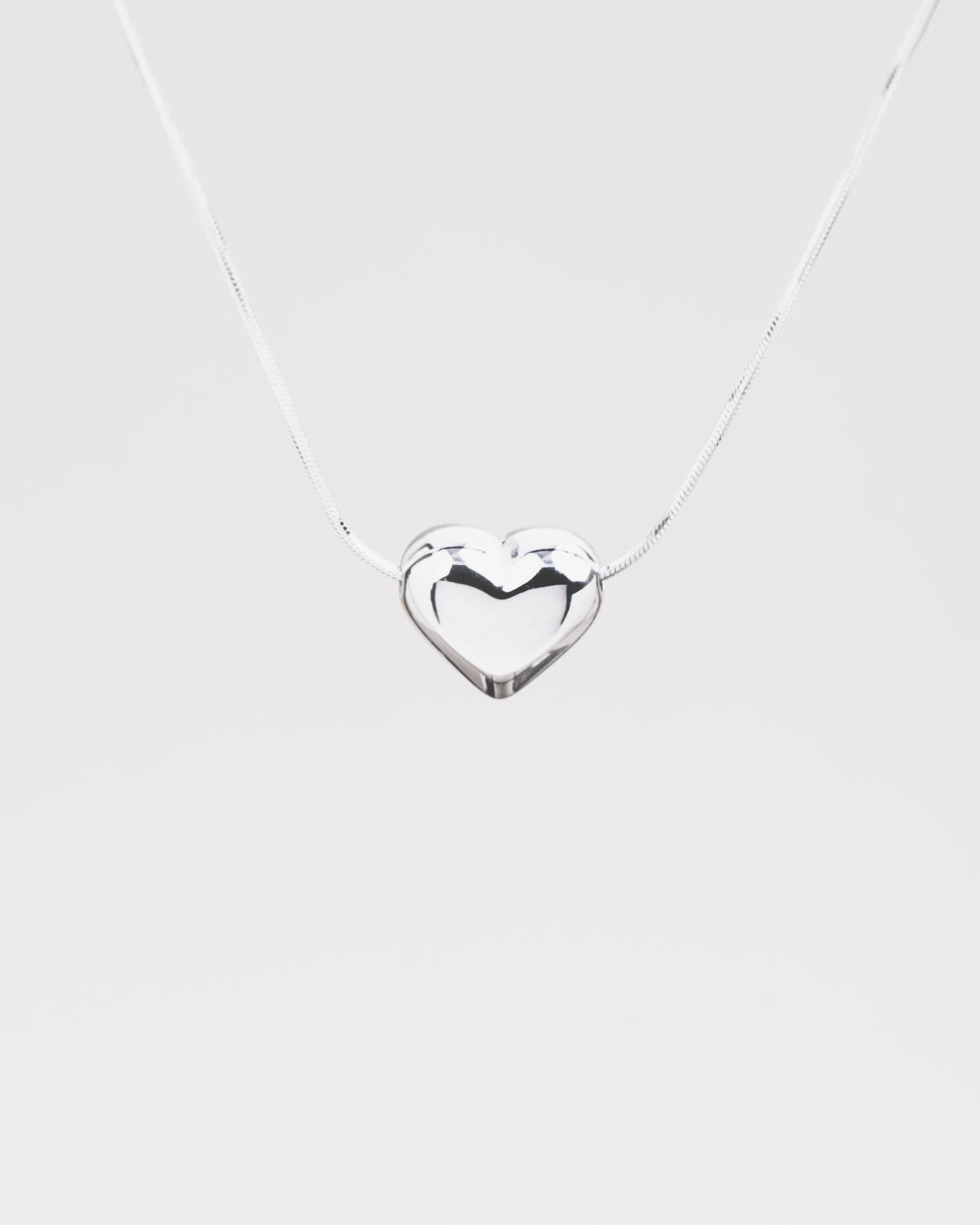 Dettaglio sul cuore bombato in acciaio inossidabile della collana Jessica nella versione argento. Il finish è molto lucido e la catenina molto sottile e fine.