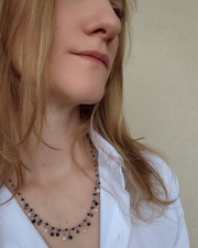 Collana Marta in acciaio inossidabile, perle e cristalli neri indossata da una modella bionda con camicia bianca.