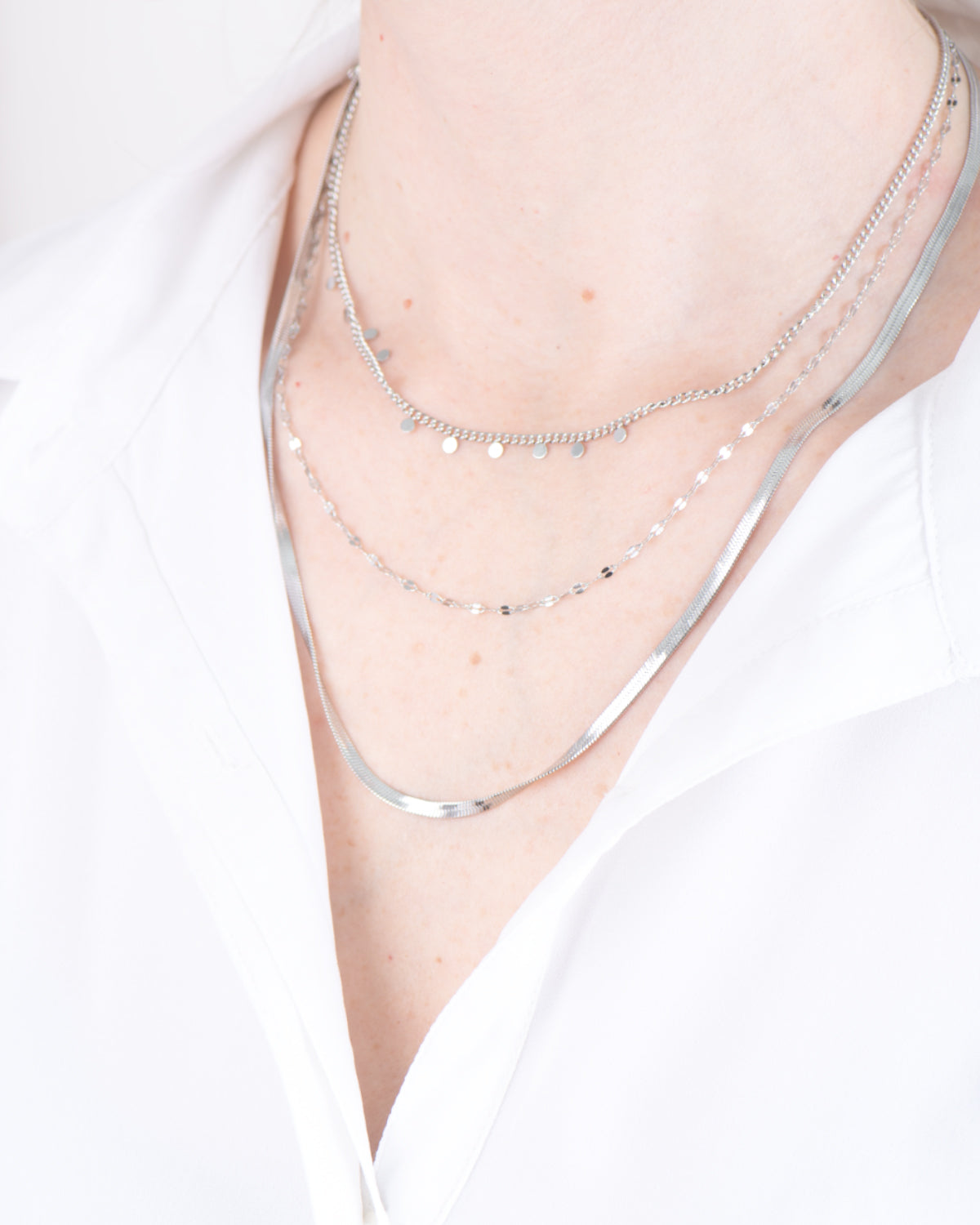 Collana Moira in acciaio inossidabile color argento. È composta da tre fili diversi: il primo, più corto, è una catenella con delle medagliette tone, il secondo è una canetenella liscia mentre il terzo, il più lungo, è un modello snake.