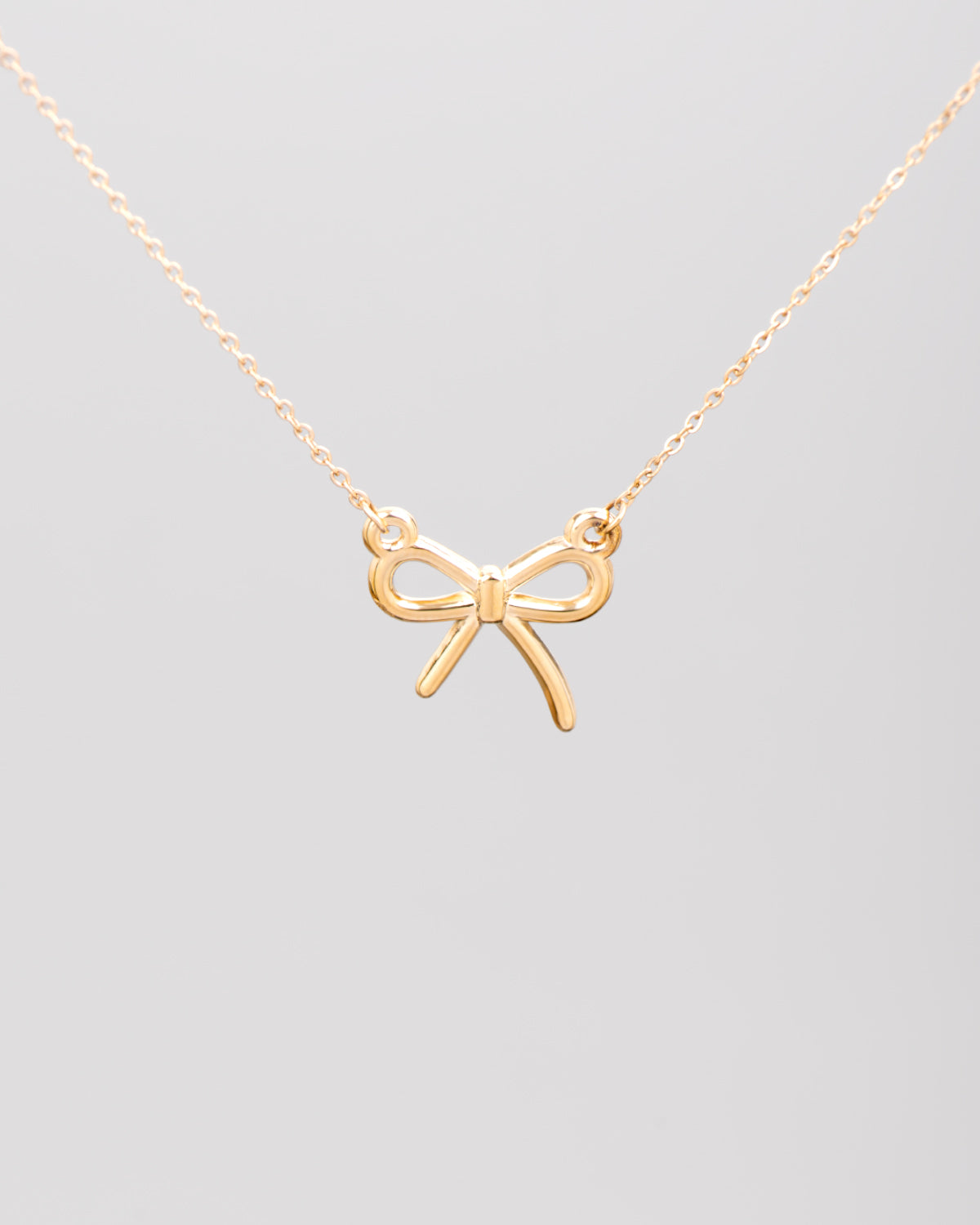 Collana Pamela in acciaio inossidabile color oro. Al centro, sorretto da due anellini tondi, si trova un fiocchetto in acciaio dal finish lucido.