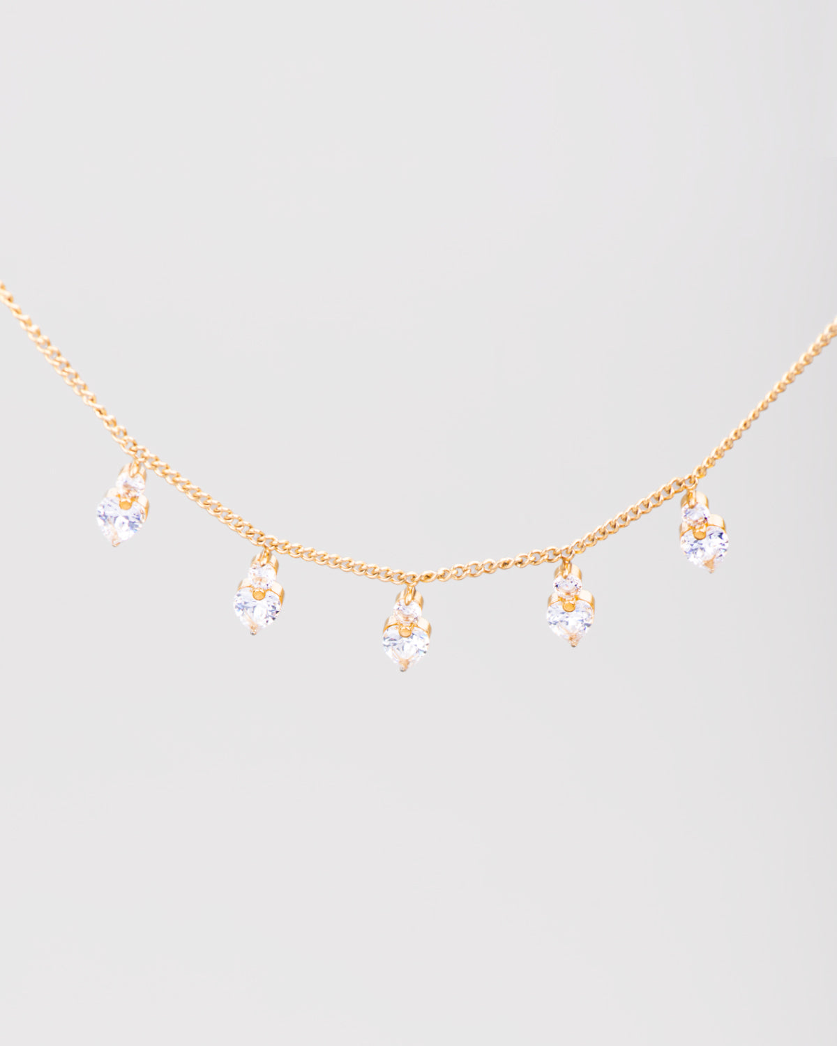 Collana Stefania in acciaio inossidabile color oro e pendenti a forma di cuore in strass. Dalla catenina pendono 5 cuoricini luminosi, sormontati a loro volta da un piccolo brillantino.