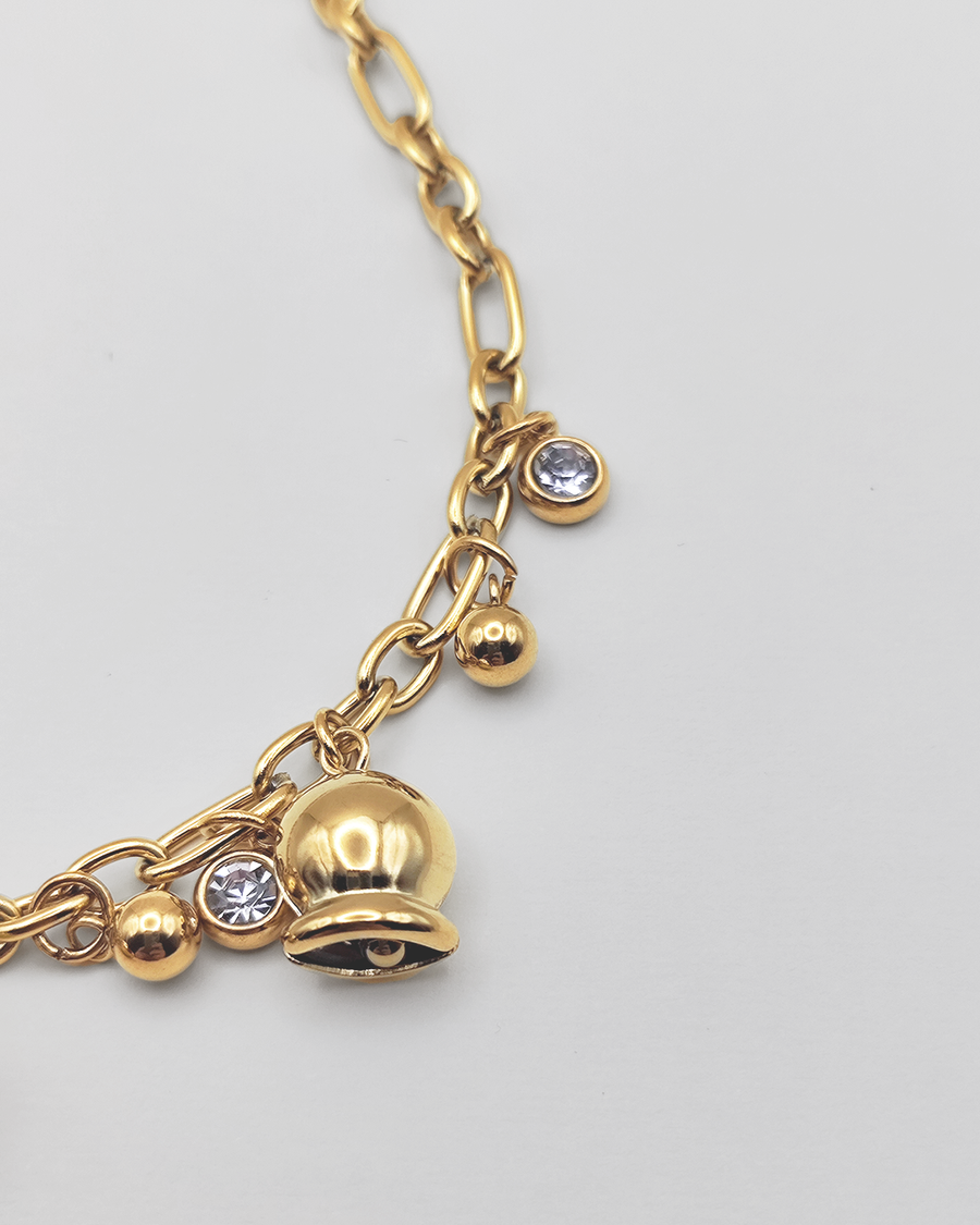 Dettaglio della Collana Federica in acciaio inossidabile color oro. E' impreziosita da campanelle e punti luce. E' rappresentata su uno sfondo grigio chiaro.