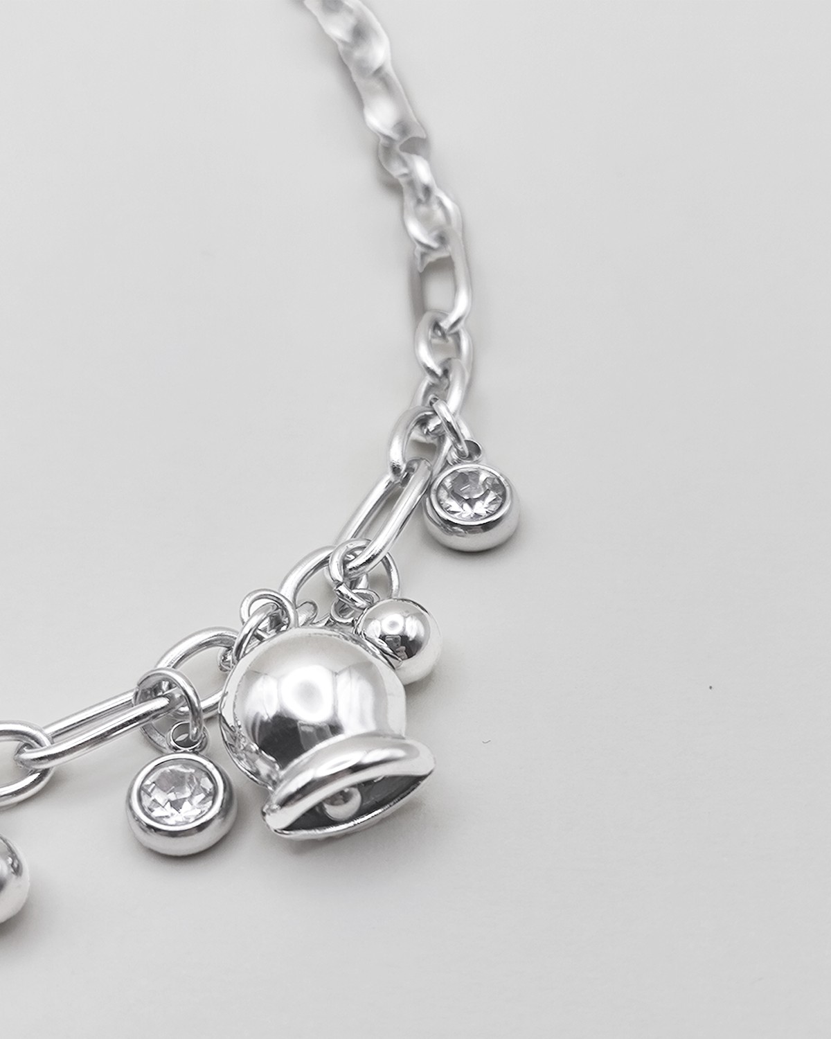 Dettaglio della Collana Federica in acciaio inossidabile color argento. E' impreziosita da campanelle e punti luce. E' rappresentata su uno sfondo grigio chiaro.