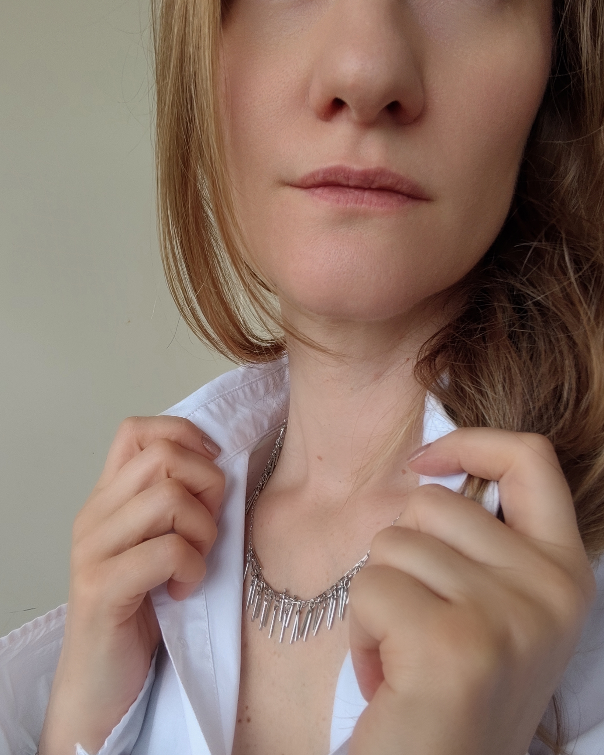 Collana Francesca in acciaio inossidabile color argento e nappine in acciaio. È indossata da una modella bionda con camicia bianca