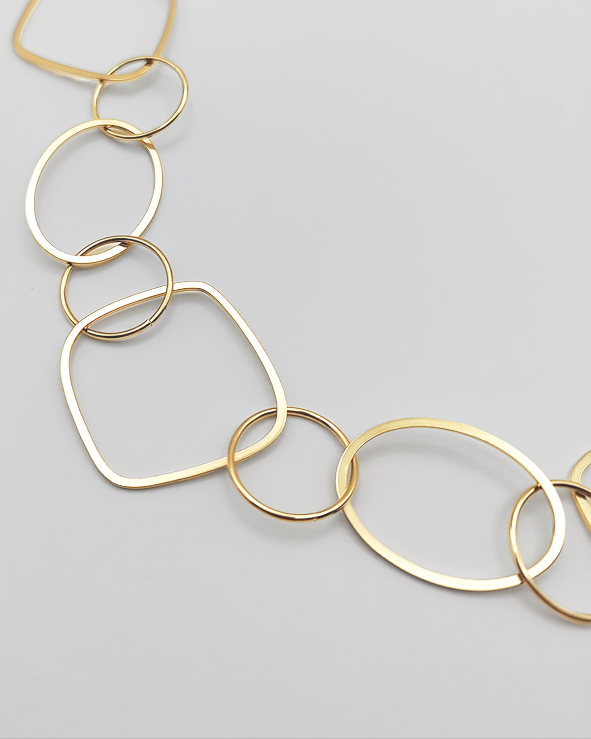 Dettaglio della Collana Liliana in acciaio inossidabile e anallergico, formata da tanti ciondoli di diverse forme geometriche. Molto fine ed elegante, è ripresa su uno sfondo grigio chiaro.