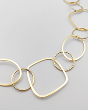 Dettaglio della Collana Liliana in acciaio inossidabile e anallergico, formata da tanti ciondoli di diverse forme geometriche. Molto fine ed elegante, è ripresa su uno sfondo grigio chiaro.