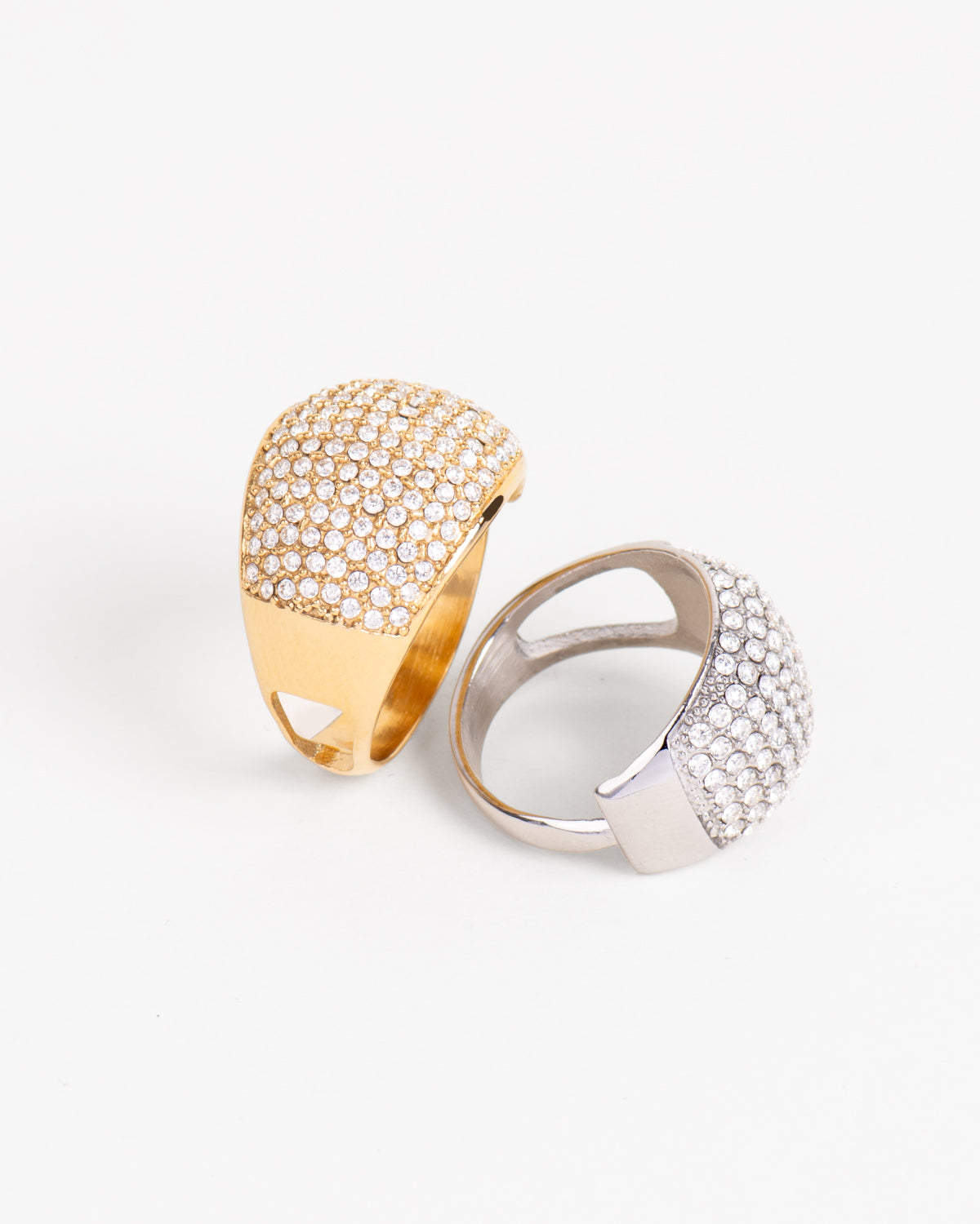 Coppia di Anelli Lucia, modello pavé in acciaio inossidabile e strass. La versione oro è ritratta in piedi e lateralmente, quella argento è distesa e ripresa in 3/4 e mostra il lato regolabile a scomparsa. Nel lato opposto c'è un'apertura geometrica che da leggerezza alla struttura. Luminoso e adatto alle situazioni eleganti. È anallergico e resistente all'acqua ed ha un prezzo accessibile per fare una bella figura spendendo poco.