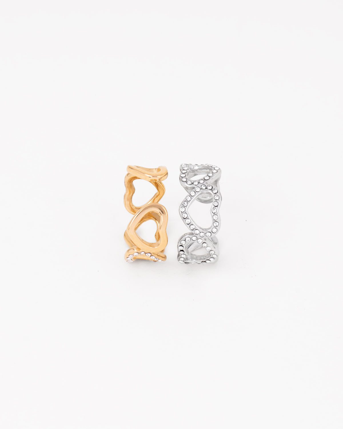 Coppia di anelli Angelica in acciaio inossidabile e strass rappresentati in piedi e affiancati su sfondo bianco nelle colorazioni oro e argento. Il modello è una fede traforata formata da cuori traforati e coperti di strass nella parte frontale. Il retro è regolabile e in acciaio liscio lucido. Sono entrambi resistenti all'acqua e anallergici.