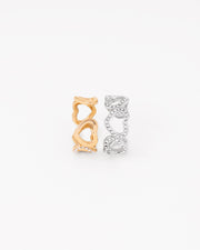 Coppia di anelli Angelica in acciaio inossidabile e strass rappresentati in piedi e affiancati su sfondo bianco nelle colorazioni oro e argento. Il modello è una fede traforata formata da cuori traforati e coperti di strass nella parte frontale. Il retro è regolabile e in acciaio liscio lucido. Sono entrambi resistenti all'acqua e anallergici.
