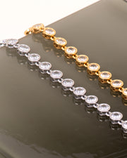 Coppia di bracciali Alessia, modello tennis con strass e castoni rotondi e piatti, senza griffe. Sono sia eleganti che sportivi e nella foto risaltano in quanto poggiati su uno sfondo nero lucido. Anche loro sono in materiale anallergico e resistente all'acqua.