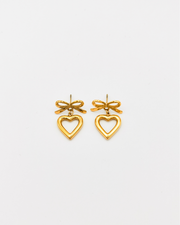 Orecchini Emma in acciaio inossidabile color oro. Sono formati da un fiocchetto che si fissa al lobo con una chiusura a perno, e un pendente a forma di cuore traforato.