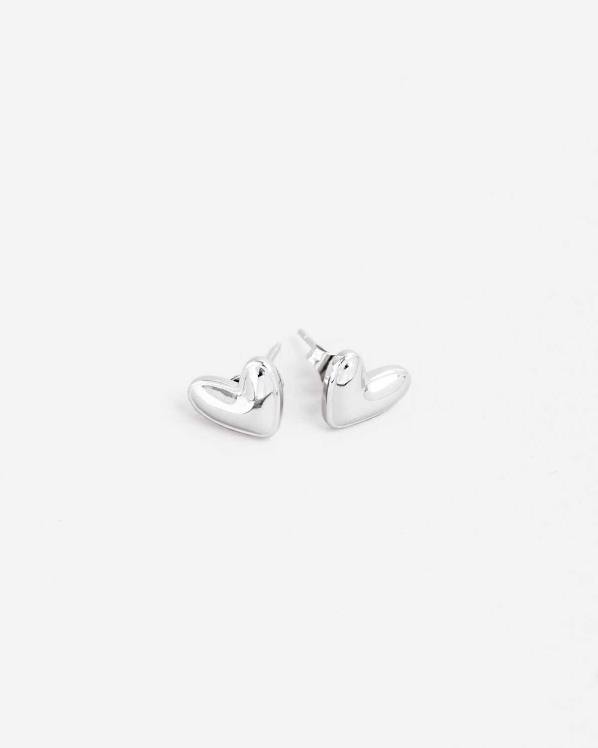 Orecchini Linda in acciaio inossidabile color argento e forma a cuore irregolare. Hanno un finish lucido e sono rappresentati adagiati sul fianco in posizione speculare.