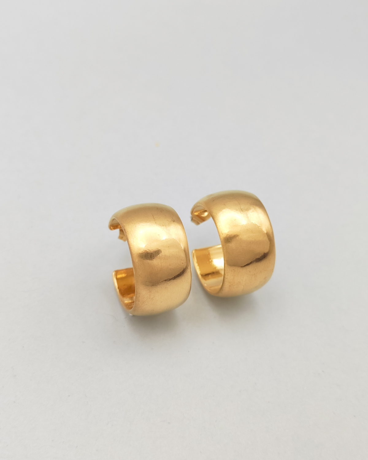 Orecchini Susanna in acciaio inossidabile anallergico color oro. Hanno un design a cerchio, sono molto spessi ma il diametro è contenuto. Hanno un finish opaco e sono rappresentati  in 3/4 verso destra.