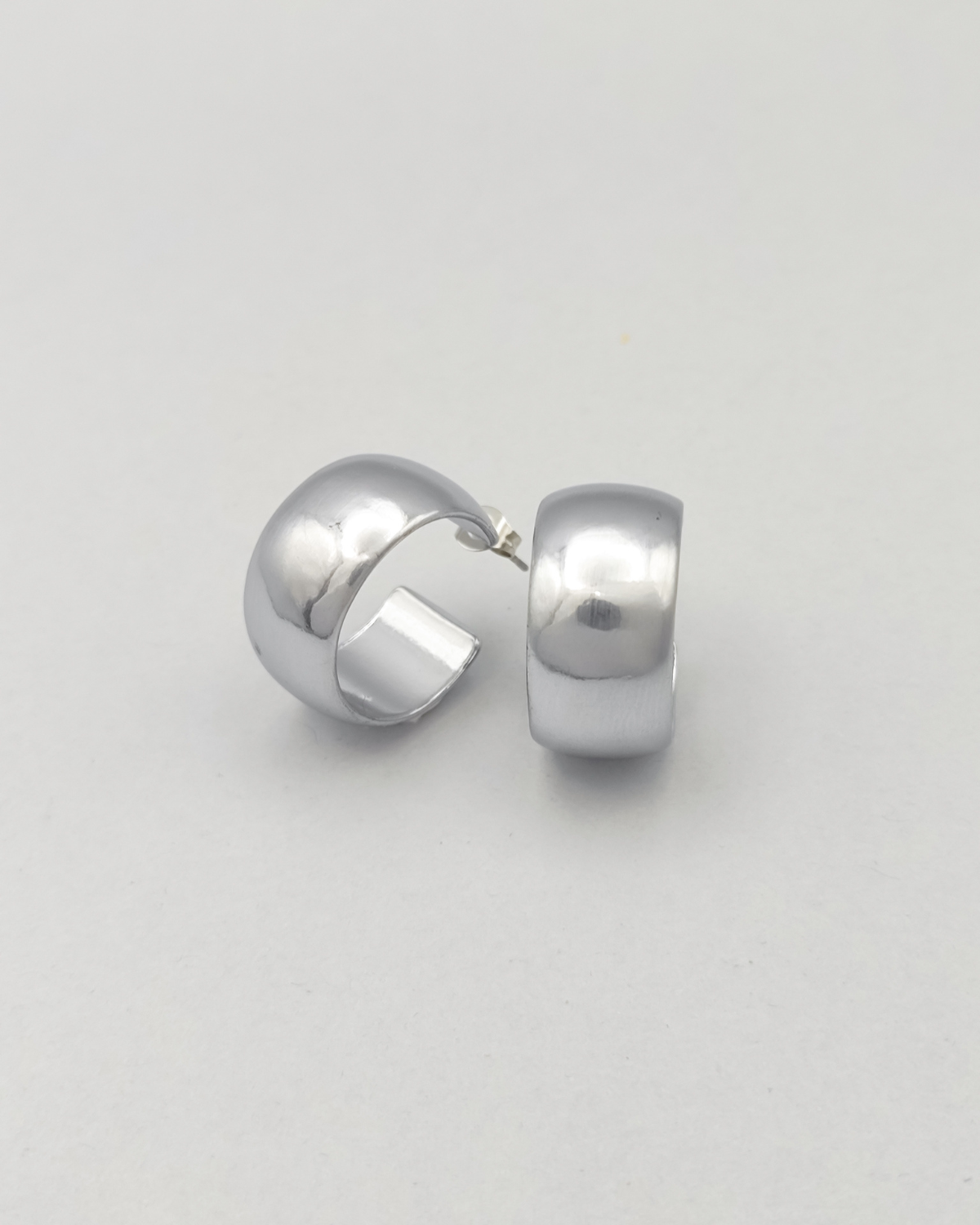 Orecchini Susanna in acciaio inossidabile anallergico color argento. Hanno un design a cerchio, sono molto spessi ma il diametro è contenuto. Hanno un finish opaco. L'orecchino di destra è rappresentato frontalmente mentre quello di sinistra è ripreso in 3/4