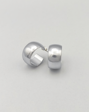 Orecchini Susanna in acciaio inossidabile anallergico color argento. Hanno un design a cerchio, sono molto spessi ma il diametro è contenuto. Hanno un finish opaco. L'orecchino di destra è rappresentato frontalmente mentre quello di sinistra è ripreso in 3/4