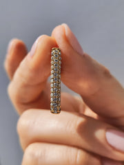 Dettaglio frontale dell'orecchino Lorena che evidenzia le tre file di strass. È sorretto da una mano femminile su uno sfondo girgio.